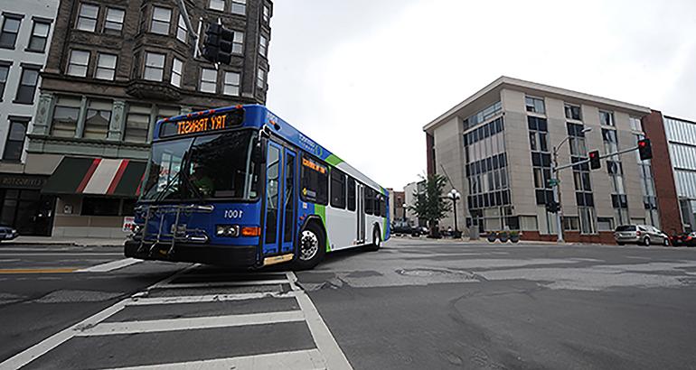 A public transit bus turning at an intersection with a marquee stating, Try Transit.